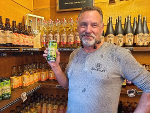 Loren Taves from Taves Estate Cidery holding a can of gooseberry apple cider